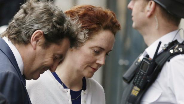 Eine Frau mit roten Haaren in Begleitung eines Mannes und eines Polizisten.