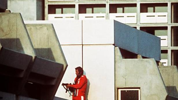 Ein Mann in roter Trainingsjacke mit einer Waffe auf einem Dach während des Münchner Olympia-Attentats 1972.