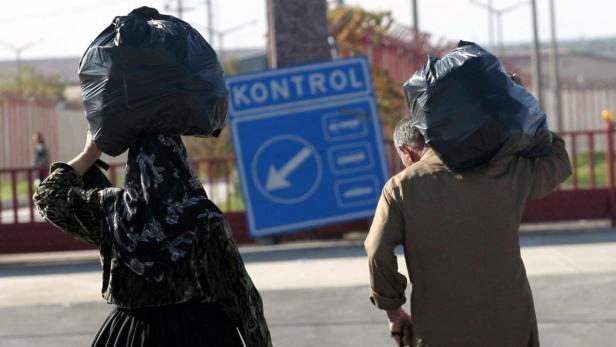 Eine Frau und ein Mann tragen schwere Säcke an einem Kontrollpunkt.