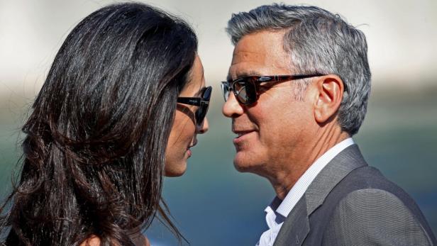 Amal und George Clooney stehen einander gegenüber.