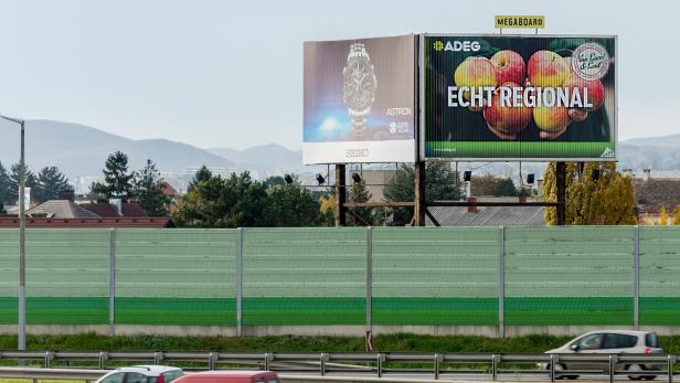 Eine Autobahn mit Autos und einer großen Werbetafel für Seiko und ADEG im Hintergrund.