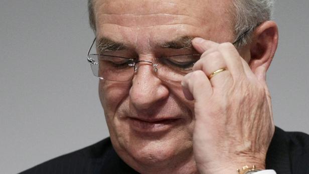 Ein älterer Mann mit Brille berührt nachdenklich seine Stirn.
