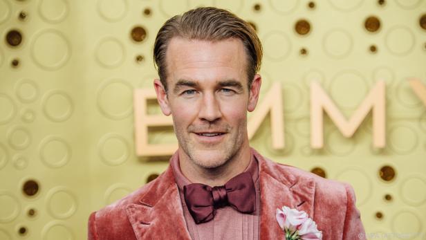 James Van Der Beek in einem rosa Samtanzug vor einem Emmy-Hintergrund.