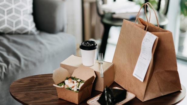 Eine Mahlzeit zum Mitnehmen mit Salat, Onigiri und Kaffee auf einem Tisch.
