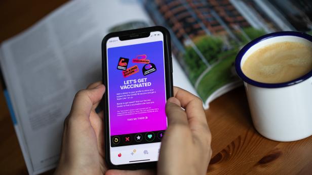 Eine Person hält ein Smartphone mit einer Anzeige für COVID-19-Impfungen in der Hand.