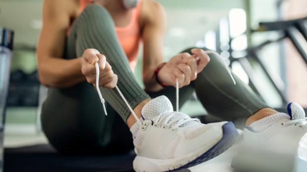 Close-up of sportswoman tying shoelace in a gym.