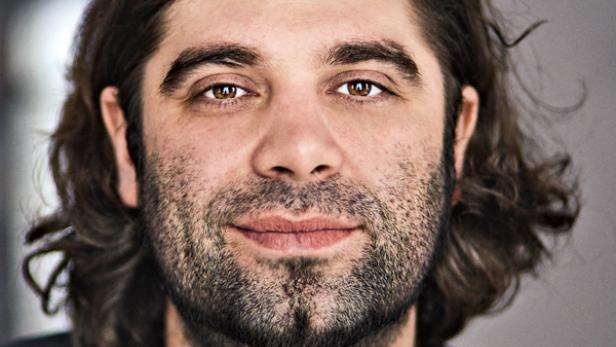 Porträt eines Mannes mit braunen Augen und dunklem, gewelltem Haar.