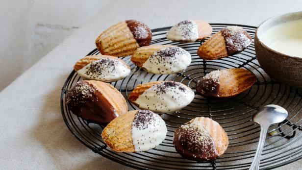 Madeleines mit Schokoladen- und Zuckerguss auf einem Kuchengitter.