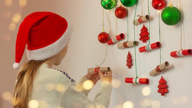 Ein Mädchen öffnet ein Kästchen bei einem Adventkalender.