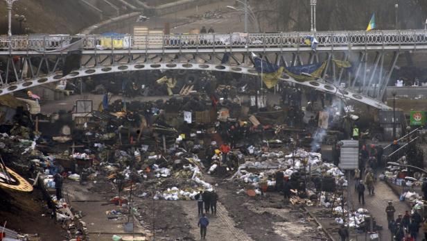 Eine zerstörte Straße in Kiew, Ukraine, mit Barrikaden und Trümmern unter einer Brücke.