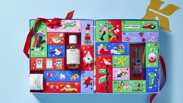 Ein geöffneter Kiehl's Adventskalender mit verschiedenen Hautpflegeprodukten und festlichen Illustrationen.