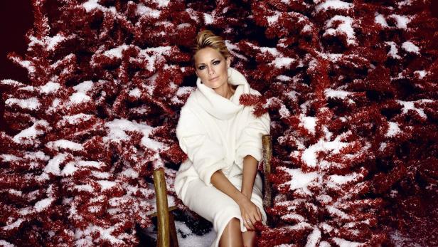 Helene Fischer posiert vor einem rot-verschneiten Weihnachtsbaum.