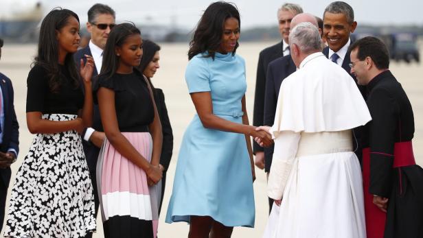 Michelle Obama begrüßt Papst Franziskus mit einem Händedruck, während Barack Obama lächelt.