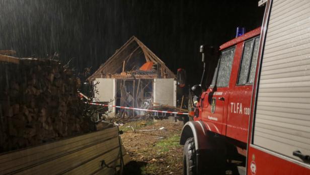Ein beschädigtes Gebäude mit einem Feuerwehrwagen im Vordergrund bei Regen.