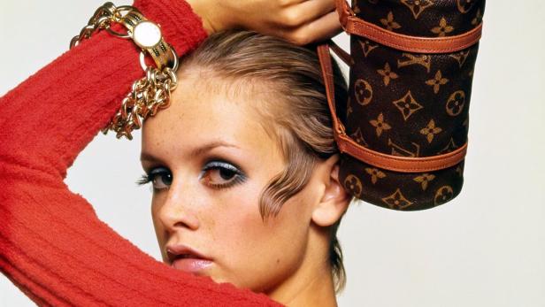 Twiggy posiert mit einer zylinderförmigen Louis Vuitton Handtasche auf dem Kopf.
