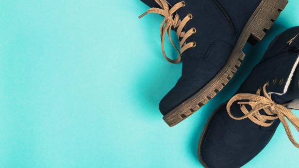 Zwei dunkelblaue Schnürstiefel auf hellblauem Hintergrund.