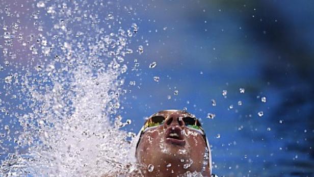 Ein Schwimmer mit Schwimmbrille taucht aus dem Wasser auf.