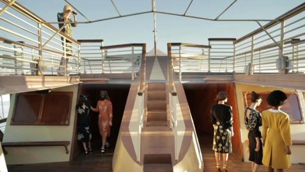 Mehrere Frauen in Kleidern auf dem Deck eines Schiffes.