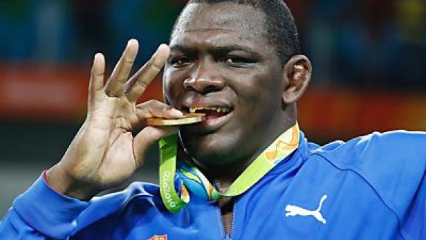 Ein kubanischer Athlet bei den Olympischen Spielen beißt in seine Goldmedaille.