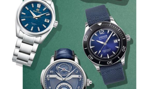 Eine Auswahl verschiedener Armbanduhren mit blauen Zifferblättern auf einem grünen Hintergrund.