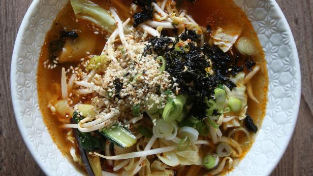 Eine Schüssel Ramen-Suppe mit Gemüse, Sprossen, Algen und Sesamkörnern.
