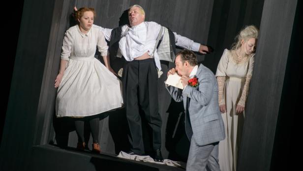 Eine Theaterszene mit vier Darstellern in historischen Kostümen auf einer schrägen Bühne.