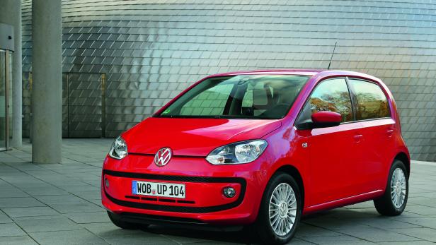 Ein roter VW Up steht vor einem Gebäude mit silberner Fassade.