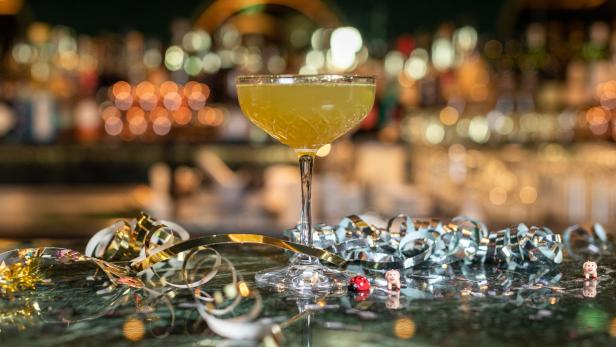 Ein „Old Cuban“-Cocktail steht auf einer Bar, dekoriert mit Partygirlanden.