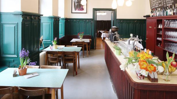 Innenansicht eines traditionellen Wiener Kaffeehauses mit Tischen, Stühlen und einer Bar.