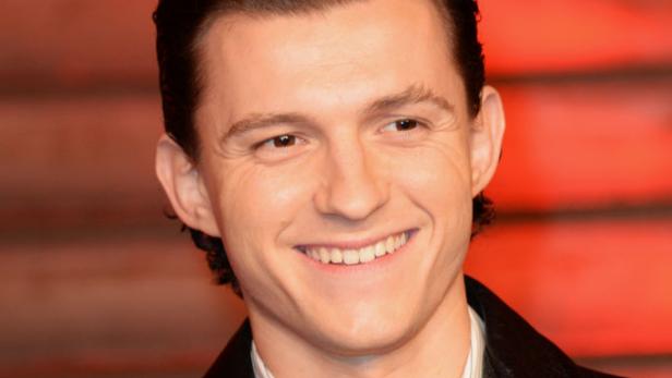 Tom Holland lächelt in einer schwarzen Lederjacke.