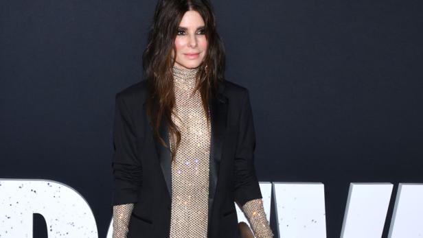 Sandra Bullock posiert in einem glitzernden Overall und Blazer auf dem roten Teppich.