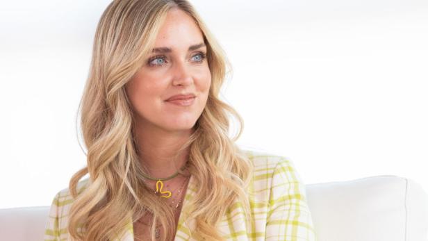 Chiara Ferragni mit blonden, gewellten Haaren und einem gelb-weiß karierten Blazer.