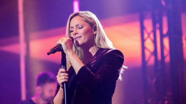 Helene Fischer singt auf einer Bühne in ein Mikrofon.