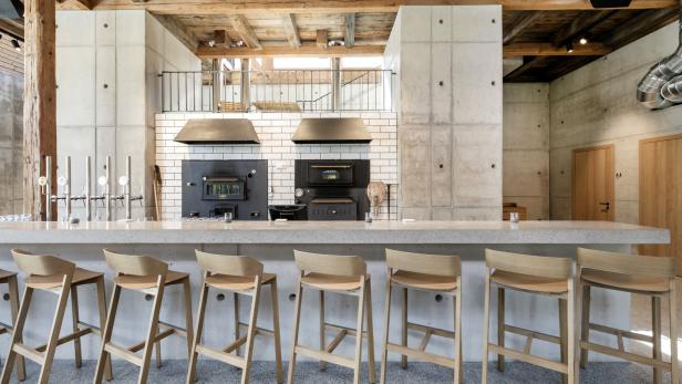 Eine Bar mit Hockern und zwei Öfen im Hintergrund.