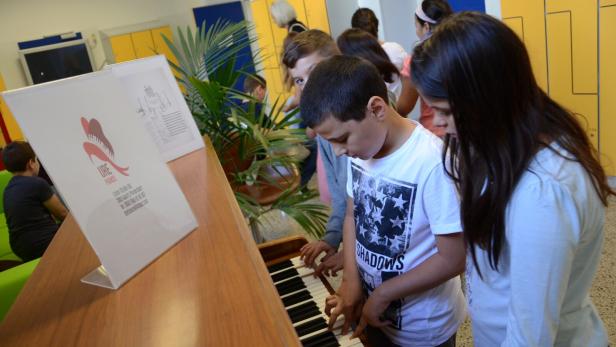 Eine Gruppe von Kindern spielt gemeinsam auf einem Klavier.