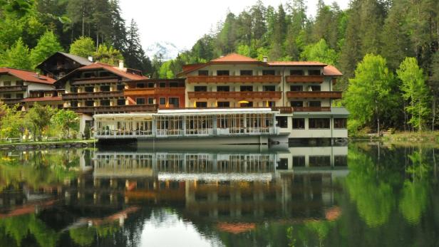 Ein Hotel am Ufer eines Sees, umgeben von Bäumen.