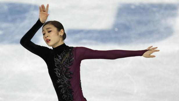 Eine Eiskunstläuferin in einem schwarz-weinroten Kleid auf dem Eis.