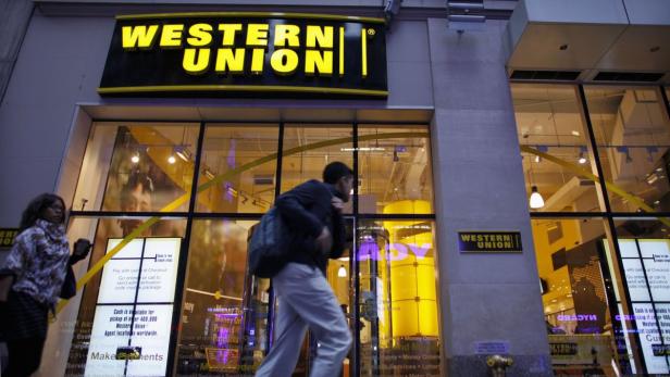 People walk past a Western Union branch at Times Square in New York November 30, 2011. REUTERS/Eduardo Munoz (UNITED STATES - Tags: BUSINESS LOGO)