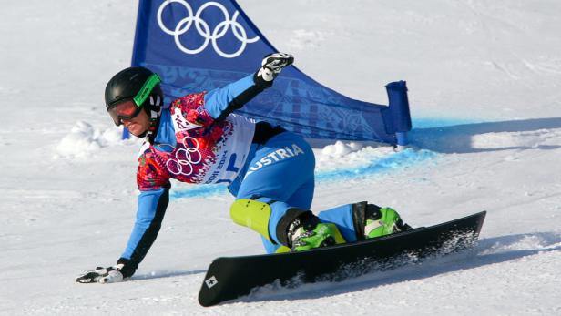 Ein Snowboarder bei einem Wettkampf, im Hintergrund die olympischen Ringe.