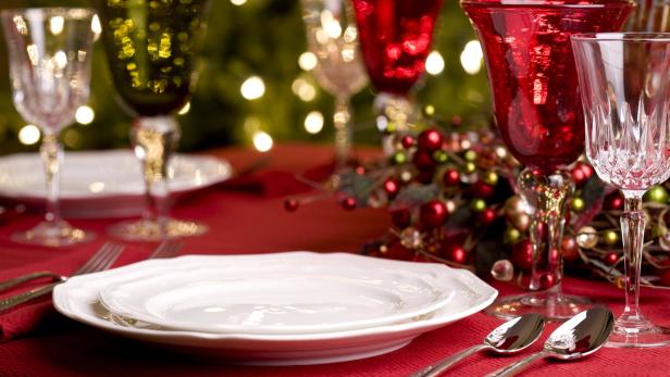 Ein festlich gedeckter Tisch mit Tellern, Gläsern und Weihnachtsdekoration.