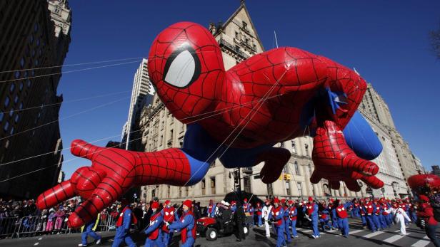 Ein riesiger Spider-Man-Ballon schwebt über eine Parade in einer Stadt.