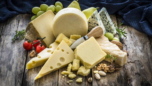 Verschiedene Käsesorten liegen auf einem Holztisch.