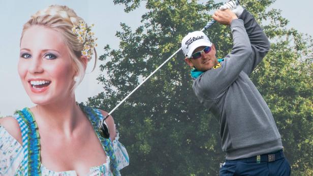 Ein Golfer schwingt seinen Schläger vor dem Hintergrund eines Dirndl tragenden Models.