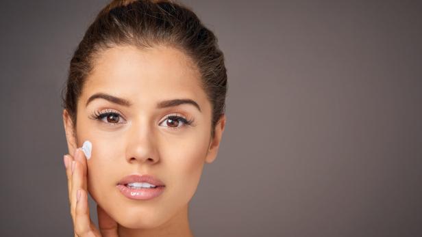 Eine Frau trägt Feuchtigkeitscreme auf ihr Gesicht auf.