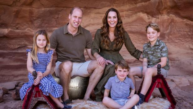Prinz William, Prinzessin Kate und ihre Kinder posieren vor einer Felswand für ein Familienfoto.