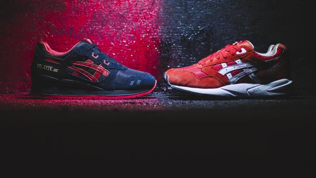 Zwei Asics-Sneaker, einer in Schwarz und Rot, der andere in Rot und Weiß, stehen nebeneinander.