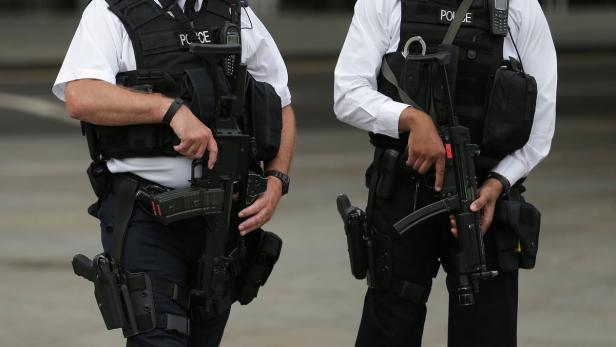 Zwei Polizisten in Uniform stehen mit Gewehren bereit.
