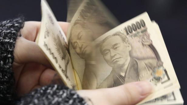 Eine Hand zählt einen Stapel japanischer 10.000-Yen-Banknoten.