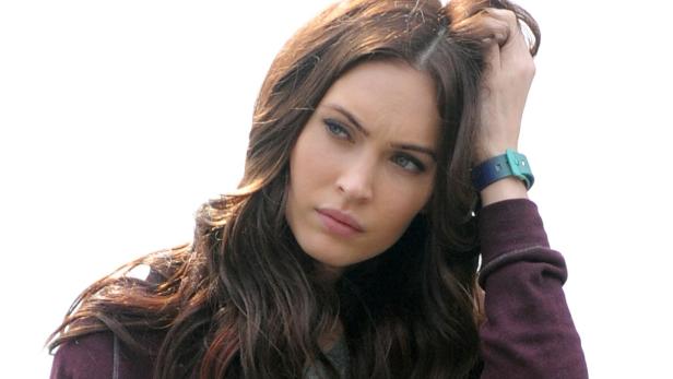 Megan Fox blickt nachdenklich und fährt sich mit der Hand durch das Haar.