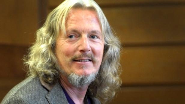 Ein Mann mit langen, blonden Haaren und Bart lächelt.